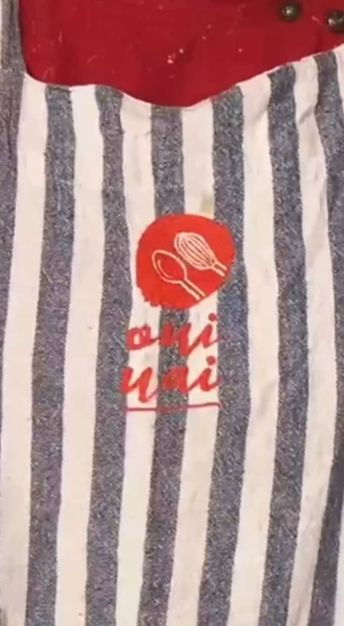 Avental listrado de azul e branco com a logo da Oui Uai estampada em vermelho.